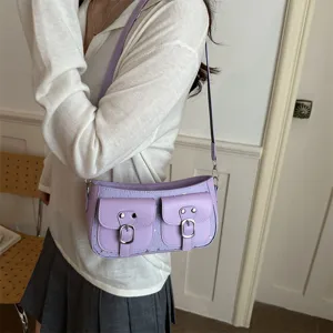 Sac bandoulière rétro violet sous les aisselles avec deux poches avant et boucles en métal.