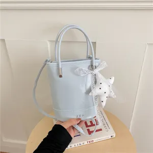 Chic light blue bucket bag with top handles, shoulder strap and cute star lace pendant.