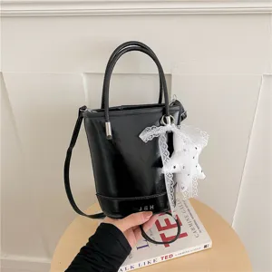Black leather bucket bag with top handles, crossbody strap and lace star charm detail.