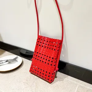 Red woven mini crossbody phone bag detail showing intricate hollowing and slim strap design.