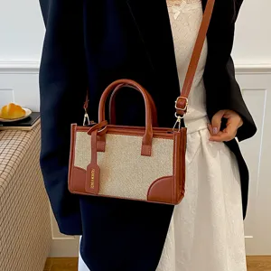 Detalle de elegante bolso cruzado para mujer en cuero PU marrón y paja trenzada con asa.