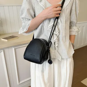 Classica borsa a tracolla in pelle nera con sottile cinturino regolabile e ciondolo chic.