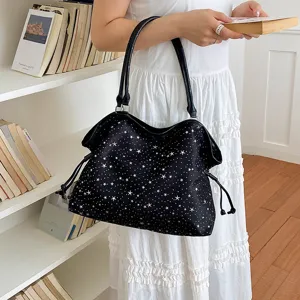 Nahaufnahme der eleganten schwarzen Schultertasche mit funkelnden weißen Sternen als Motiv.