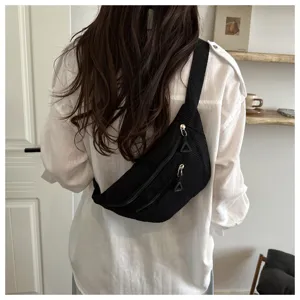 Detail view of black corduroy chest bag, casual crossbody sling bag with smooth zipper.