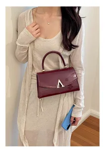 Borsa a tracolla chic in pelle verniciata bordeaux con catena dorata e chiusura a V.