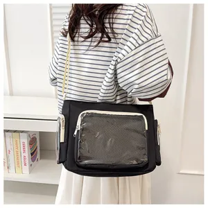 Black canvas messenger bag detail showing front clear window pocket and shoulder strap.