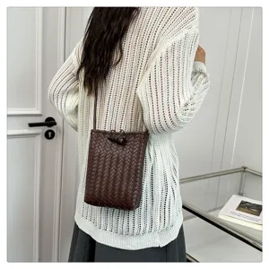 Détail de mini sac bandoulière en cuir tressé souple marron foncé et élégant.