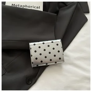 Close-up detail of a chic silver polka dot card case wallet on black blazer background.