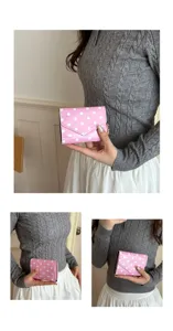 Pink polka dot patent leather wallet detail view, highlighting compact envelope flap.