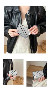 Close-up detail of the silver polka dot wallet held by hand, showcasing unique fashion style.
