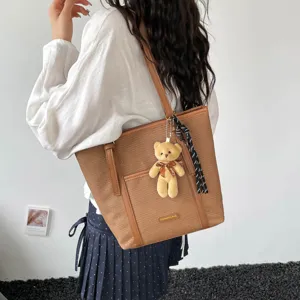 Vintage brown tote bag detail showing large capacity, cute bear pendant and stylish ribbon accent.