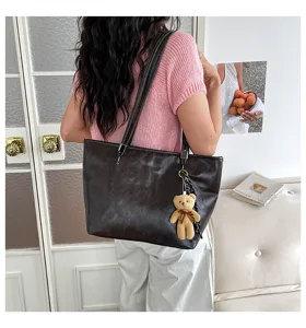 Vista dettagliata della borsa a spalla in pelle marrone scuro vintage con ciondolo.