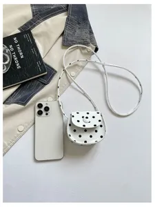 Detaillierte Nahaufnahme der weißen gepunkteten Mini Umhängetasche in einem Flat-Lay-Setup.