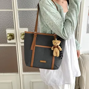 Detailed view of large capacity woven tote bag with brown PU leather trim and cute bear pendant.