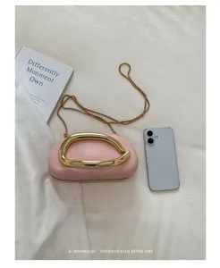 Close-up detail of the pink mini box clutch bag with unique gold metal handle and chain strap.