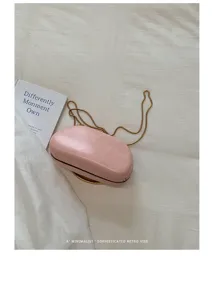 Pink box bag detail shot with elegant gold chain strap on clean white minimalist background.