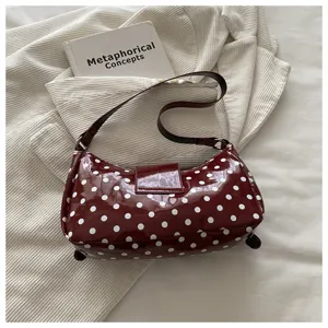Bordeauxrode lakleer schoudertas met witte stippen, elegante vintage handtas voor dames onder arm.