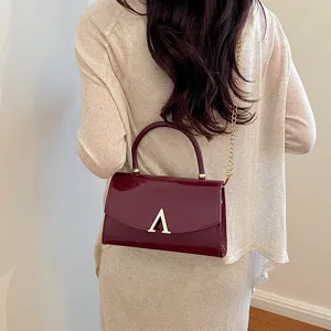 Borsa a tracolla in pelle verniciata bordeaux, dettaglio della catena e chiusura con logo V.
