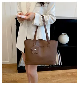 Dettaglio borsa shopper in pelle marrone, design minimalista, grande capacita e ciondolo fiore.