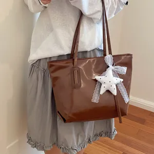 Élégant sac cabas en cuir marron avec pendentif en peluche étoile pour le travail quotidien.