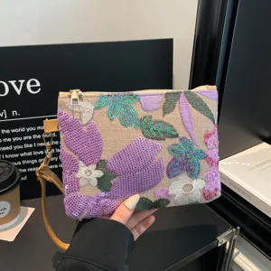 Primo piano di un'elegante pochette ricamata con paillettes e delicati dettagli floreali.