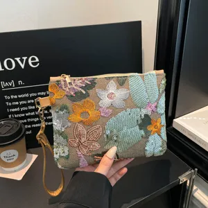 Vista dettagliata della pochette in tela ricamata con fiori e paillettes e polsiera.