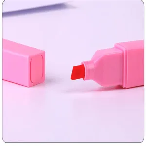 Detail en gros plan du surligneur rose a corps carre montrant la pointe biseautee rouge.