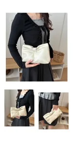 Detail view of minimalist cream white pleated bow clutch bag held by model, stylish fashion accessory.