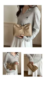 Detailed view of chic minimalist French bow clutch bag, elegant khaki leather fashion accessory.
