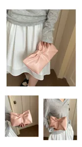 Close-up details of the elegant pink bow clutch bag, showcasing textured leather and chic style.