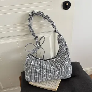 Close-up detail of black and white gingham shoulder bag with cute bow prints and ruffled strap.