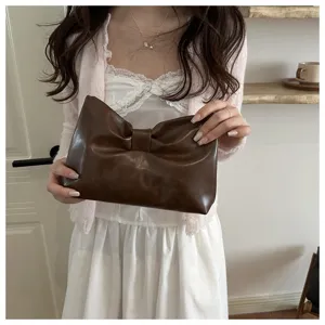 Detailed close-up view of the chic brown bow clutch bag in a cozy indoor scene, elegant style.