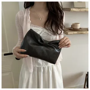 Detail view of the elegant black leather bow clutch bag, showcasing fine texture and design.