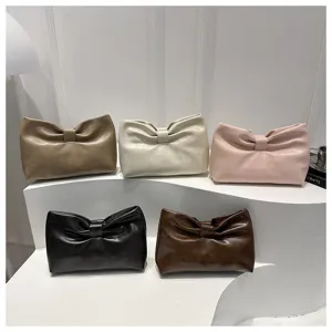 Detailed view of stylish minimalist soft leather bow clutch bags in multiple elegant chic colors.
