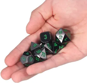 Vue détaillée de dés polyédriques en métal avec numéros verts tenus à la main pour l'échelle