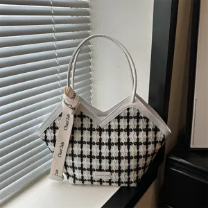 Gedetailleerd overzicht van de zwart-witte houndstooth tote bag met wit lederen afwerking.