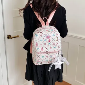Detail view of a cute cartoon printed canvas backpack with pink straps and star lace pendant.