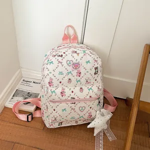 Detailed view of cute cartoon printed white student backpack with pink straps and charm.
