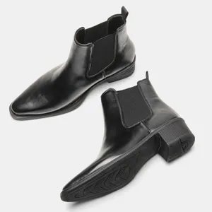 Detailansicht schwarzer Chelsea-Boots aus Leder mit rutschfester Sohle und Absatz.