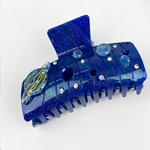 Detailed close-up view of dark blue galaxy hair claw clip with rhinestones and planet charm