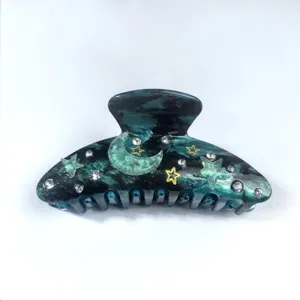 Close-up of ocean-patterned acrylic hair claw clip with star, moon, and rhinestones.