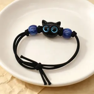 Macro view of a cute black cat charm bracelet featuring large blue eyes and beads