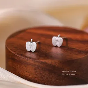 Nahaufnahme von apfelförmigen Sterling Silber Ohrsteckern auf einem dunklen Holzsockel