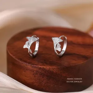 Detailaufnahme eleganter S999 Sterling Silber Ginkgoblatt-Ohrringe auf einem Holzsockel