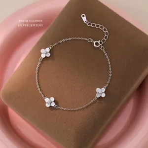 Elegantes Silberarmband mit drei weißen Kleeblatt-Anhängern auf einem Schmuckständer