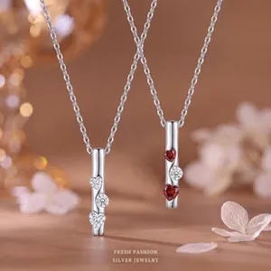 Nahaufnahme von zwei silbernen Herz-Halsketten mit Zirkonia-Steinen und Blumen.