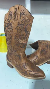 Detail van het vintage bloemenborduursel op bruine cowboylaarzen met een spitse neus