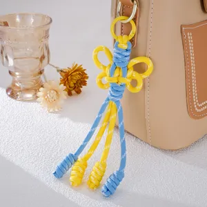 Handgefertigter gelb-blauer gewebter Schmetterlings-Taschenanhänger mit Quasten für Rucksäcke.