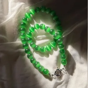 Dettaglio di una collana di perle occhio di gatto verdi con chiusura ad anello.