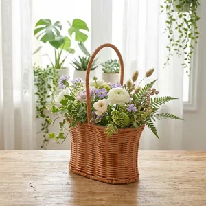 Handwoven plastic wicker flower basket with fresh ranunculus and greenery on a wooden table
